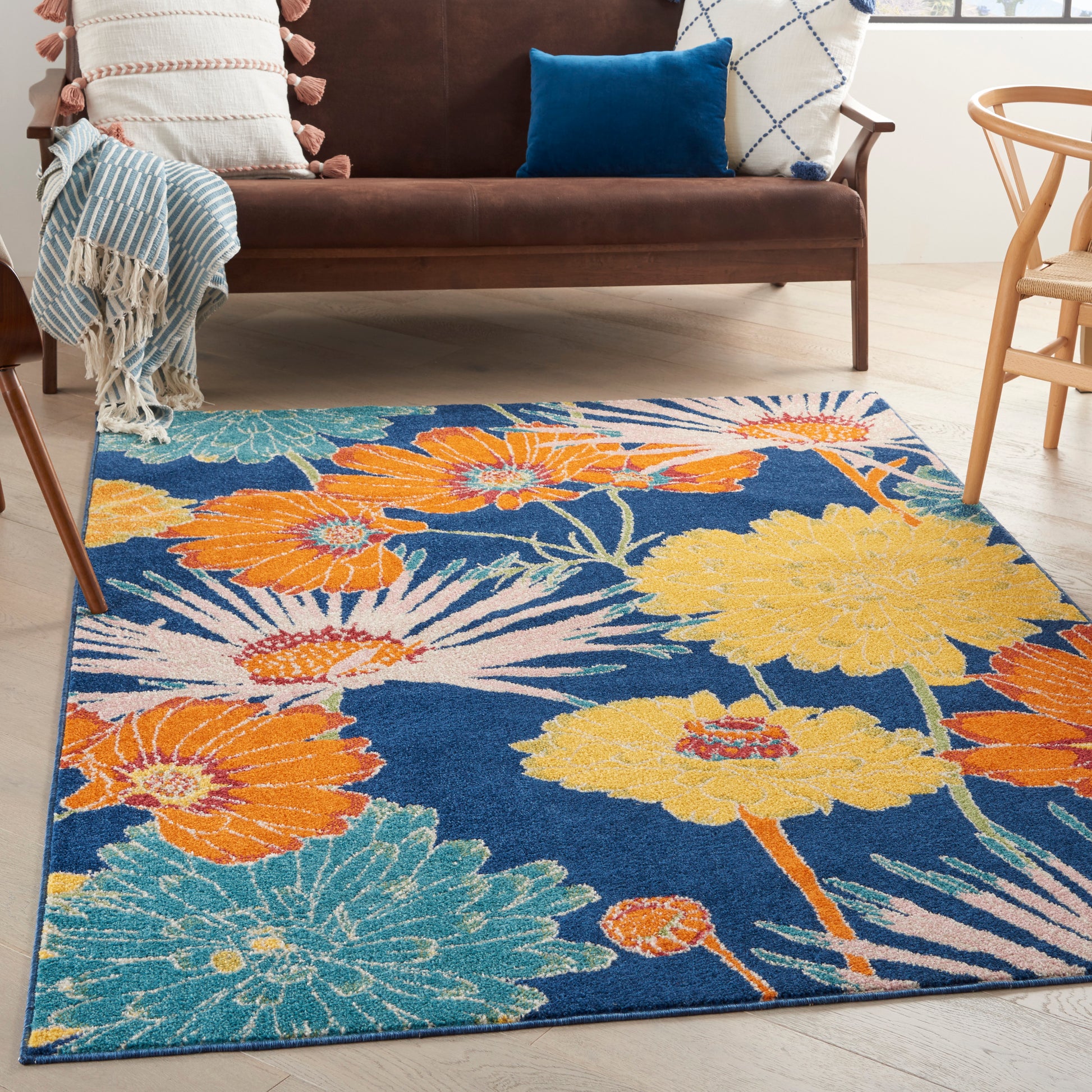 Colorful floral area rug with blue background and orange, yellow, turquoise flowers in a modern living room.