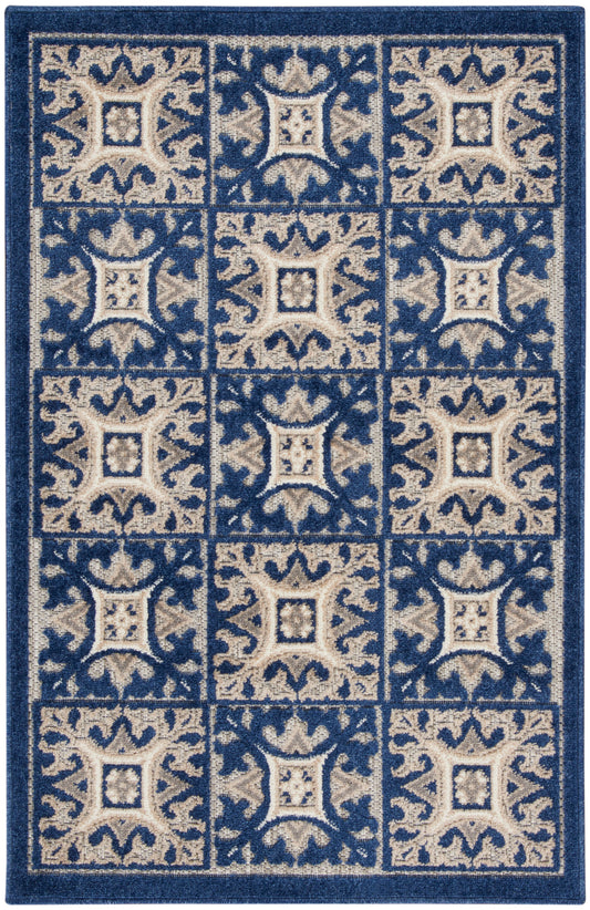 Blue and beige patterned area rug with tiled square blocks and ornate scrollwork in a grid.