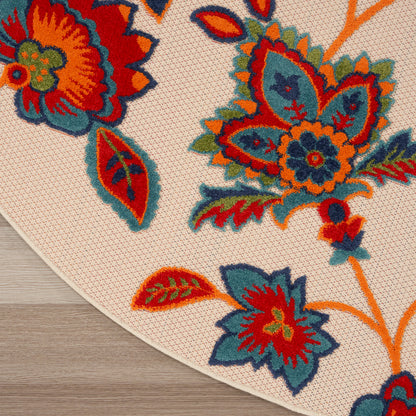 Cream round rug with bold orange, red, teal and blue floral motif and woven texture.
