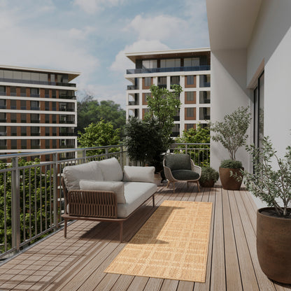 Balcony with beige cushioned wicker sofa, dark round lounge chair, potted plants, beige runner rug, overlooking modern apartments.