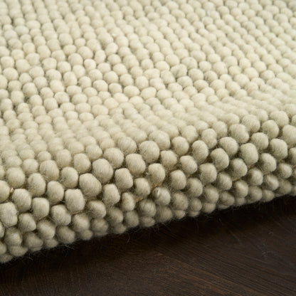 Cream boucle rug with dense bubble tuft texture on dark wooden floor.
