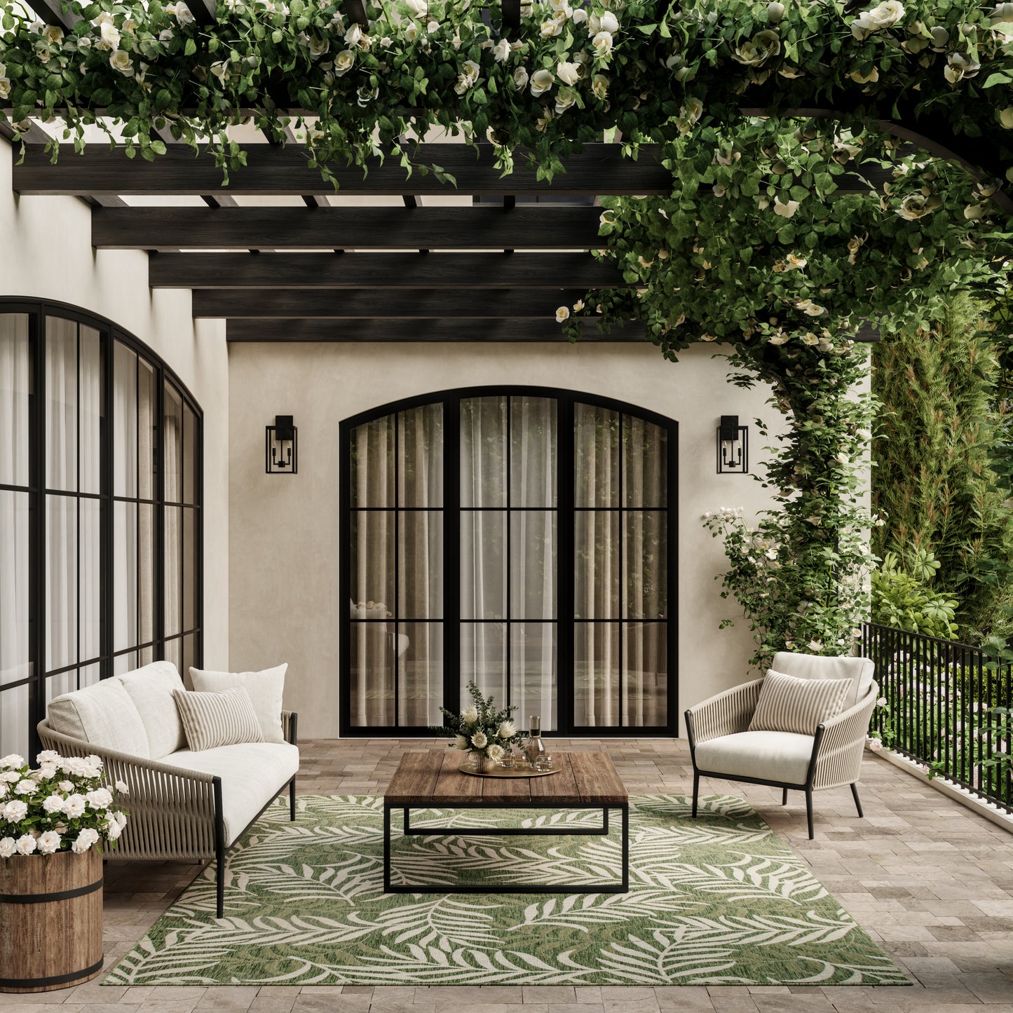Outdoor patio with black arched doors, cream wicker seating, a wooden coffee table, and a green leafy rug.
