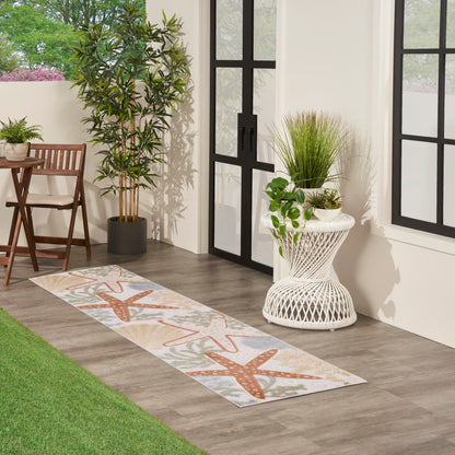 Long indoor-outdoor runner rug with orange starfish motif on beige background, beside glass doors with potted plants.