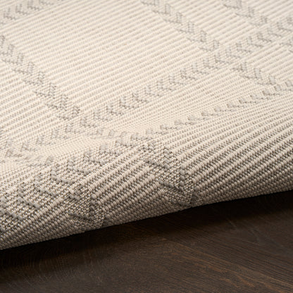 Beige geometric woven rug with taupe chevron & diamond patterns, textured surface on dark wood floor.