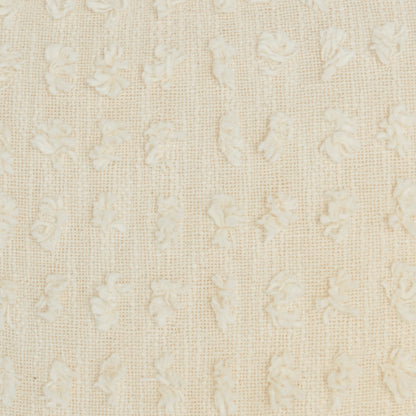 Cream-colored woven fabric with tiny raised floral motifs and a soft damask-like texture, suitable for upholstery or curtains.