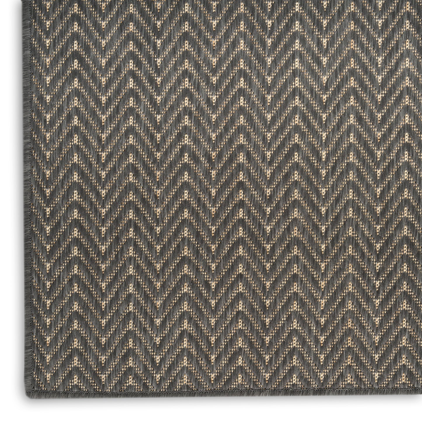 Close-up of dark gray and beige chevron woven rug, textured zigzag pattern in neutral hues, modern geometric style.