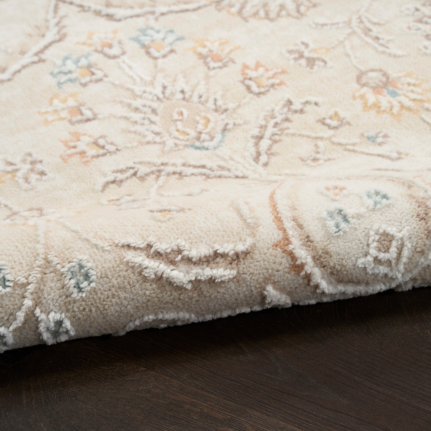 Cream Persian-style rug with pastel peach and pale blue floral pattern, plush pile, fringed edge.