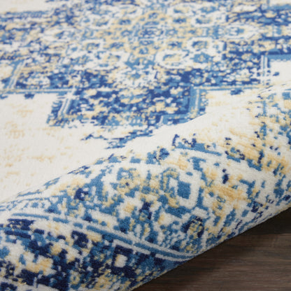 Close-up of a blue and ivory geometric patterned rug with a rolled edge on a wooden floor.