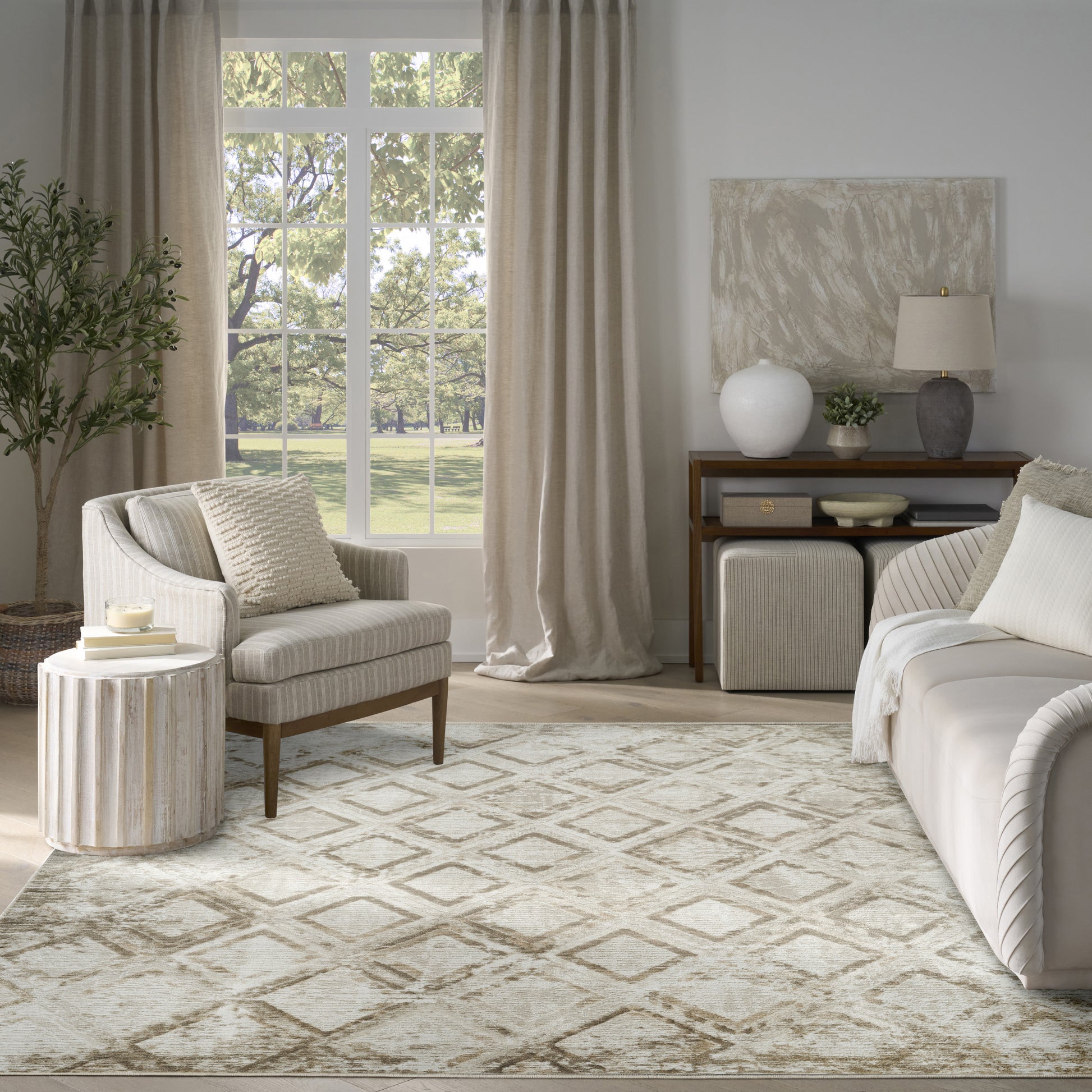 Neutral living room with beige sofa, striped armchair, geometric rug, window with beige curtains, and decorative console.