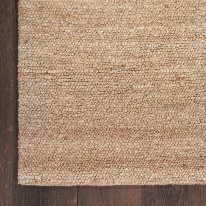 Beige textured loop-pile rug edge on dark wood floor; cozy neutral-toned home decor.