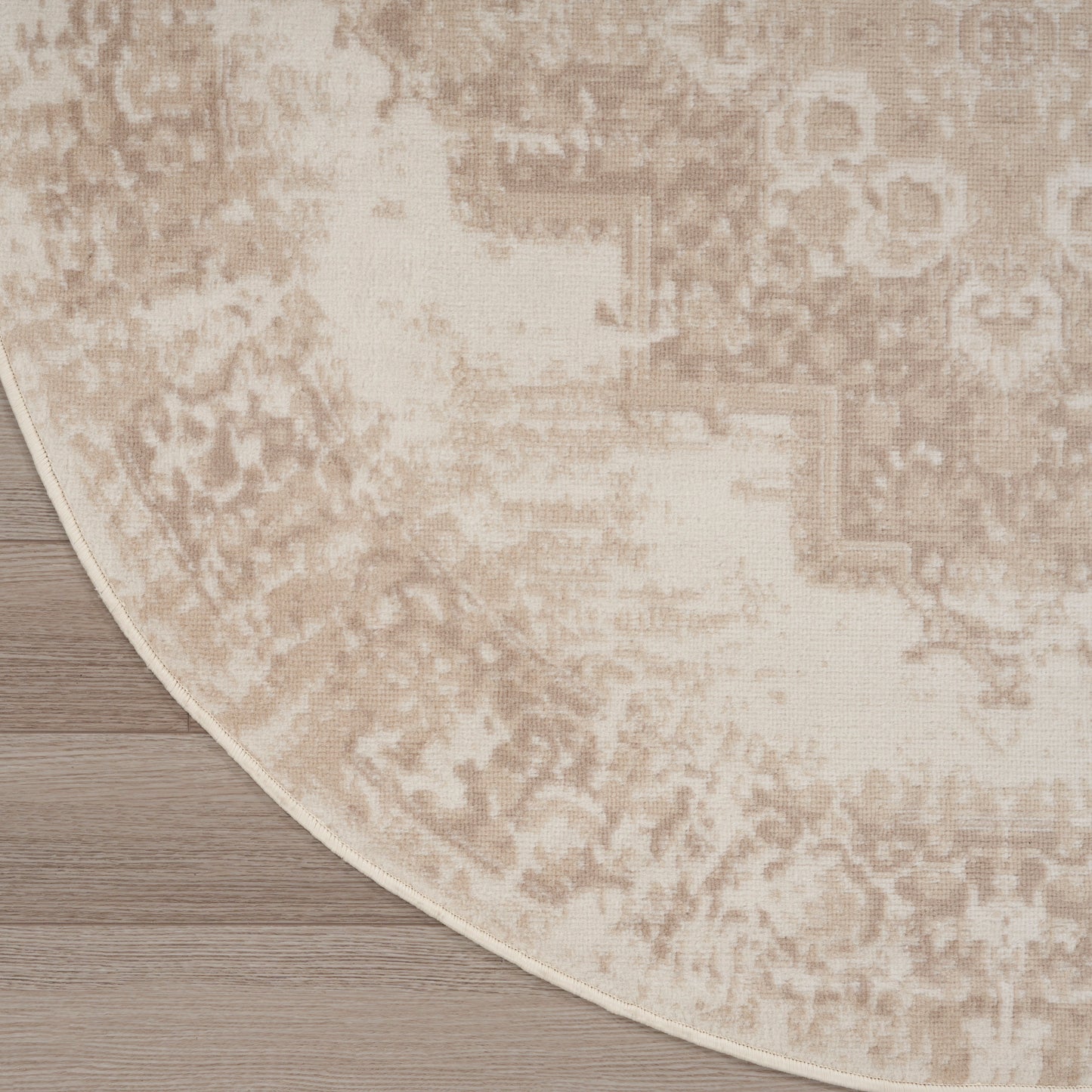 Beige round rug with a distressed vintage pattern on wood floor
