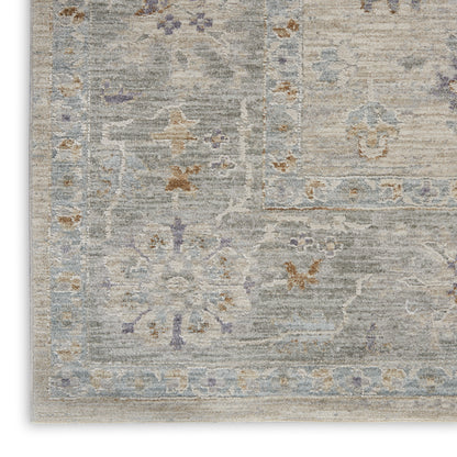 Soft gray-blue oriental area rug with faded floral medallions and decorative cream, lavender, and tan borders.