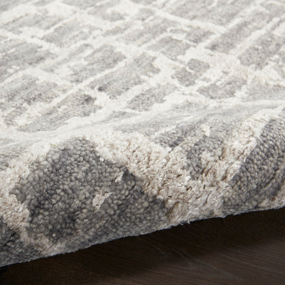 Plush gray & ivory geometric area rug with textured pile, edge visible on dark wood floor.