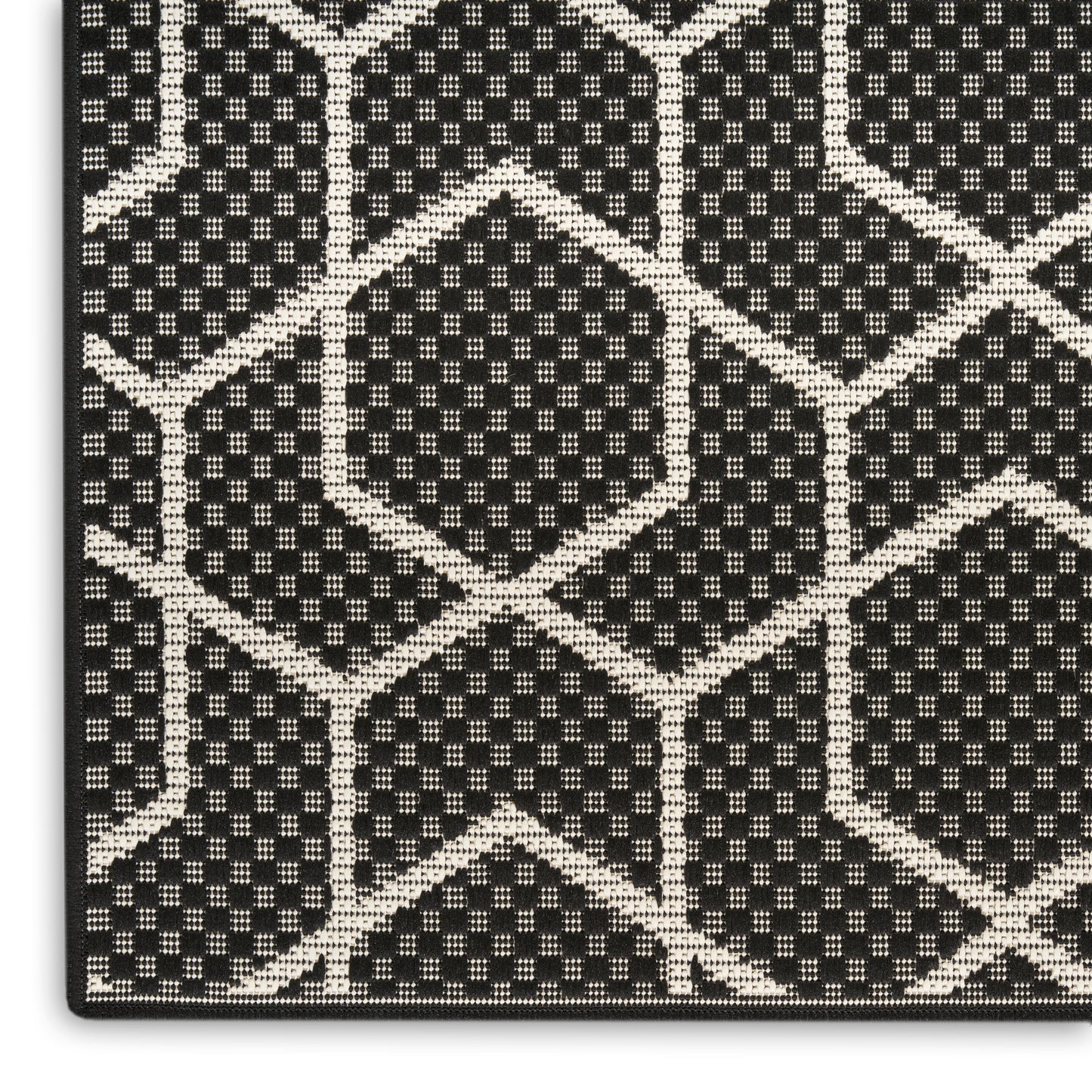 Close-up of black fabric with white geometric lattice of hexagons and diamonds; woven, textured textile.