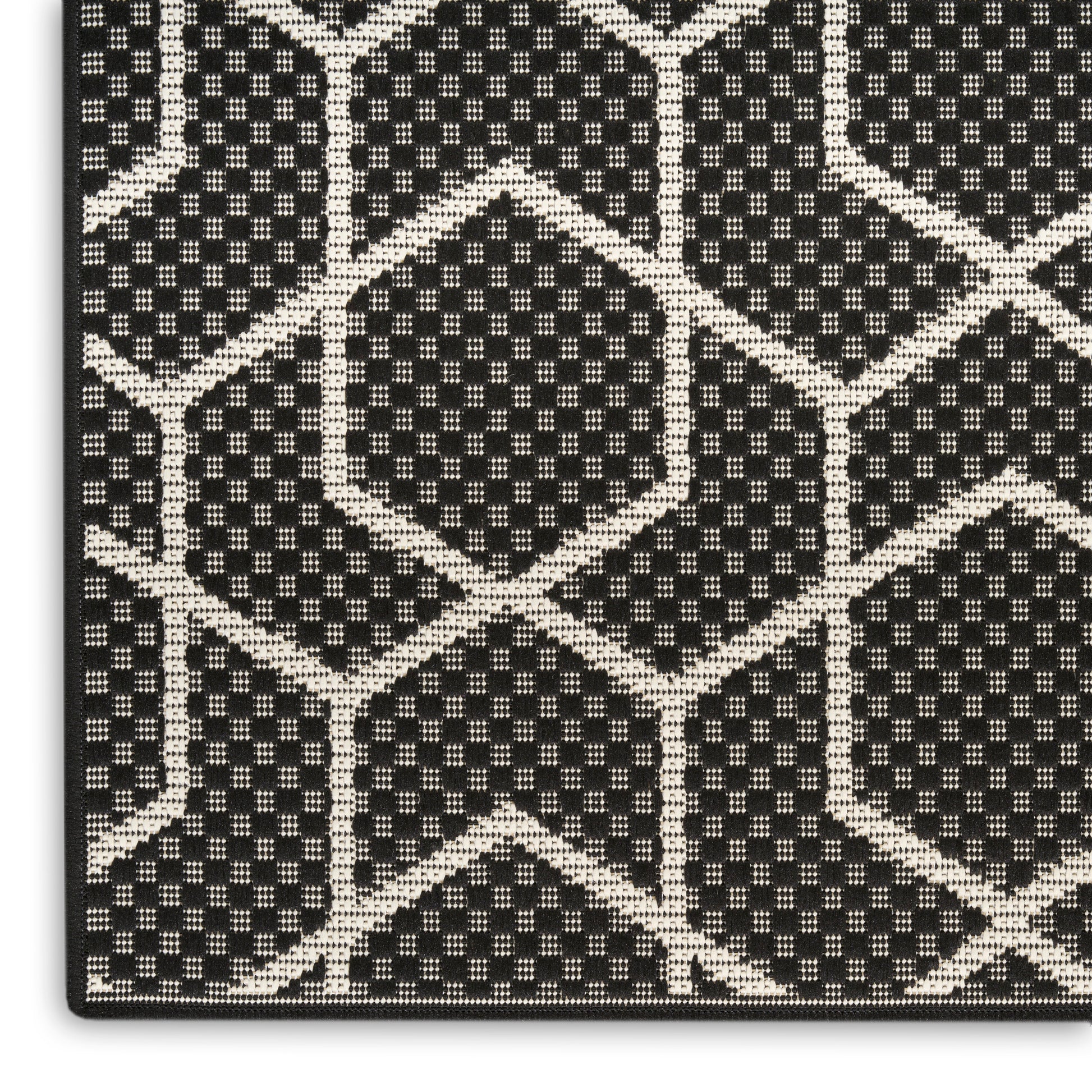 Close-up of black fabric with white geometric lattice of hexagons and diamonds; woven, textured textile.