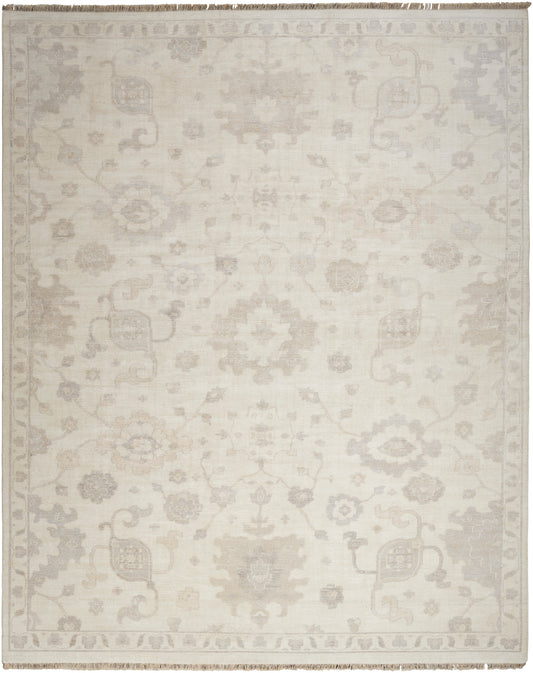 Ivory area rug with a subtle gray damask floral pattern and fringed border.