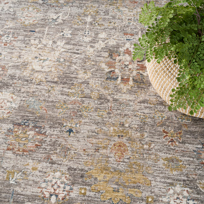 Muted grey vintage floral area rug with yellow, blue and rust accents; a potted fern in a woven basket sits in the corner.