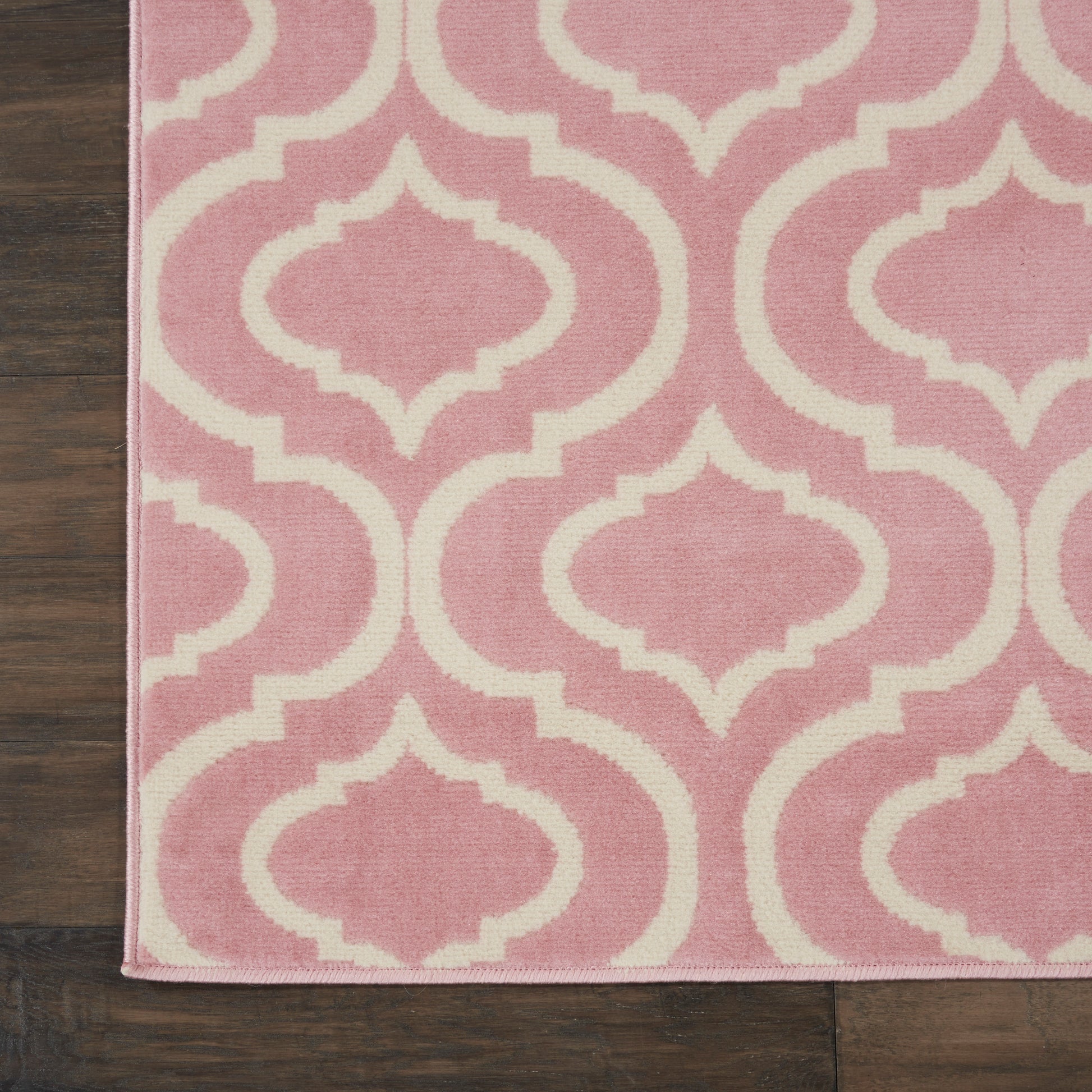 Pink rectangular rug with white trellis lattice pattern, 7' x 10'.