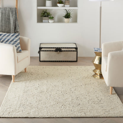 Cream textured area rug in a modern living room with beige armchairs and a vintage beige storage trunk.