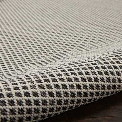 Beige and black woven rug with a textured checker pattern; flat-weave for modern home decor.