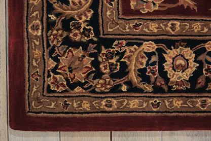 Rectangular Persian-style rug with burgundy, ivory, and gold floral border on a wooden floor.