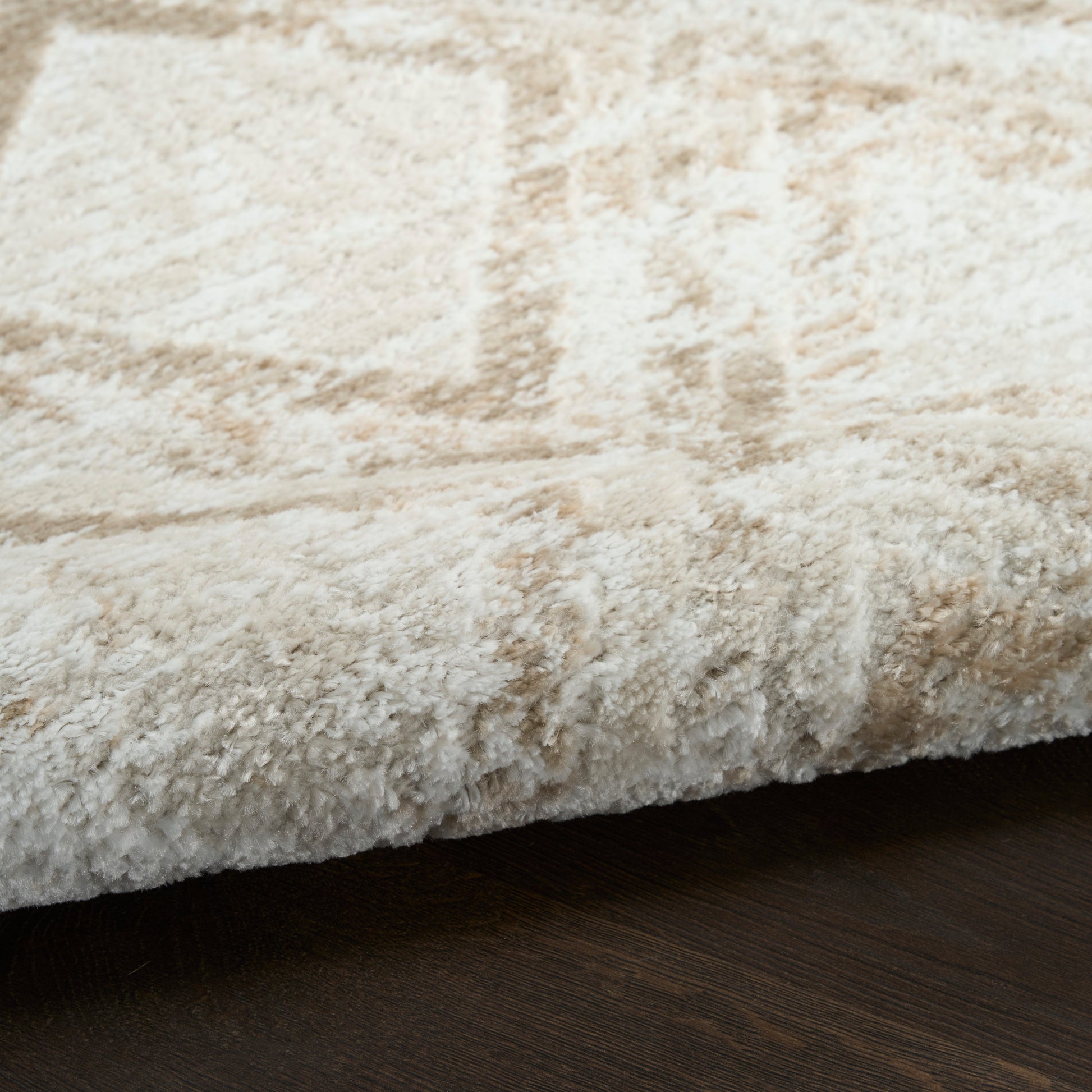 Cream shag rug with plush high-pile texture on dark wood floor, modern cozy style, 8' x 10'.
