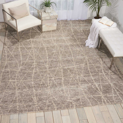 Beige woven rug with geometric criss-cross pattern on light wood floor; white cushioned chairs and a white tufted bench.