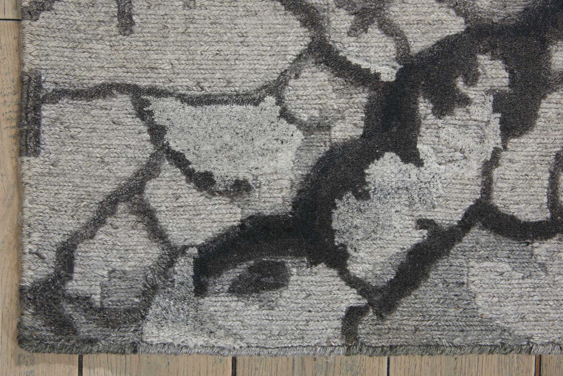 Gray abstract area rug with dark charcoal pattern on textured pile; modern decor.
