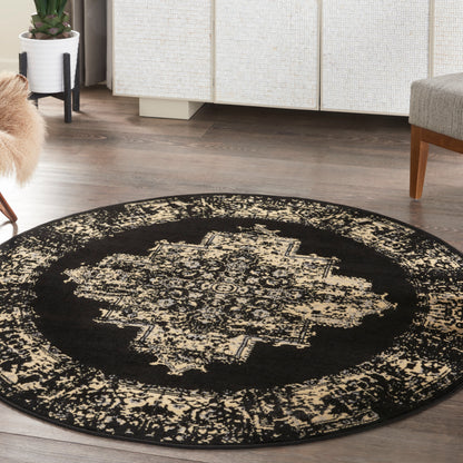 Round black oriental-style rug with beige distressed medallion pattern on dark wood floor.