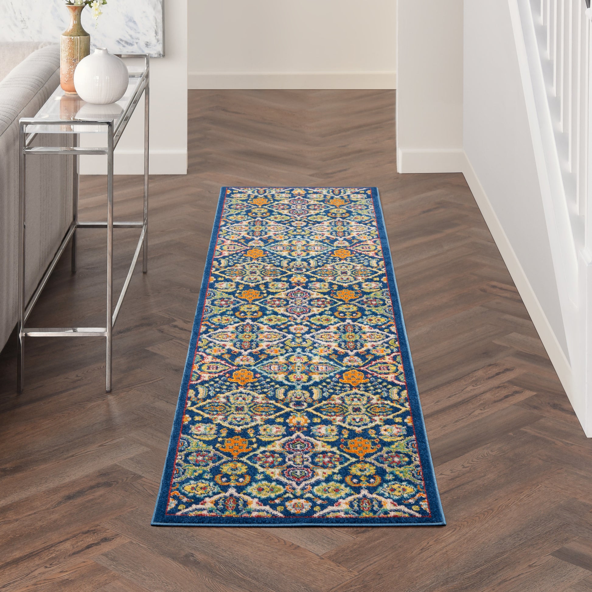 Vibrant geometric hallway runner rug with blue border on dark herringbone floor, modern decor.