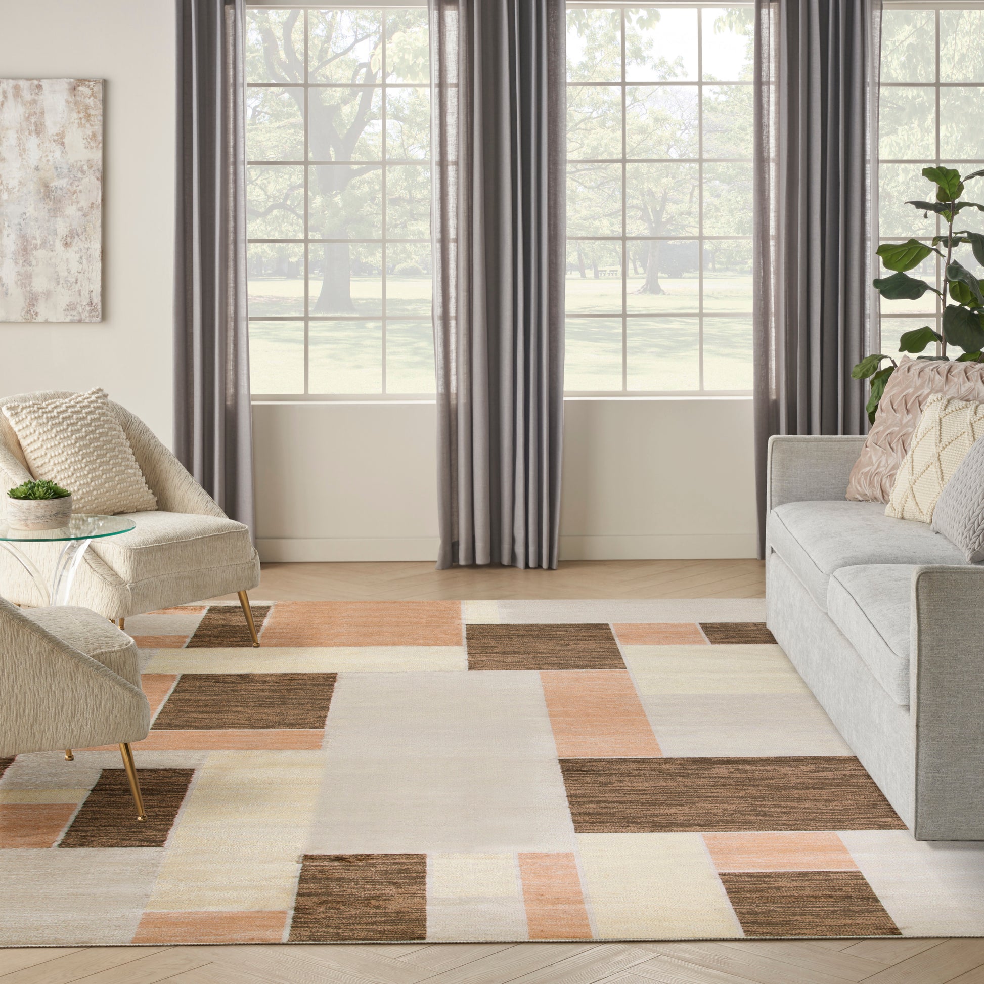 Modern living room with patchwork cream, tan, brown & peach area rug, gray sofa, beige chair, glass coffee table, curtains
