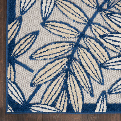 Navy and cream botanical rug with large leaf pattern, textured weave and dark blue border on wood floor.