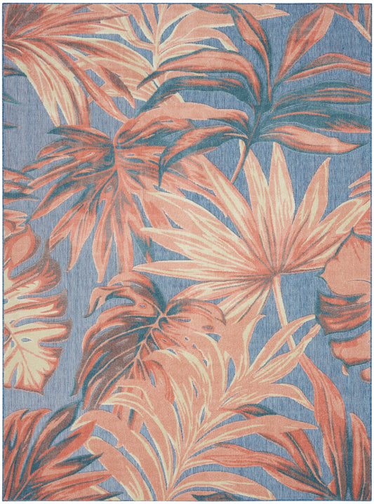 Rectangular coral-peach tropical leaf rug on blue background; woven texture, bold botanical print.