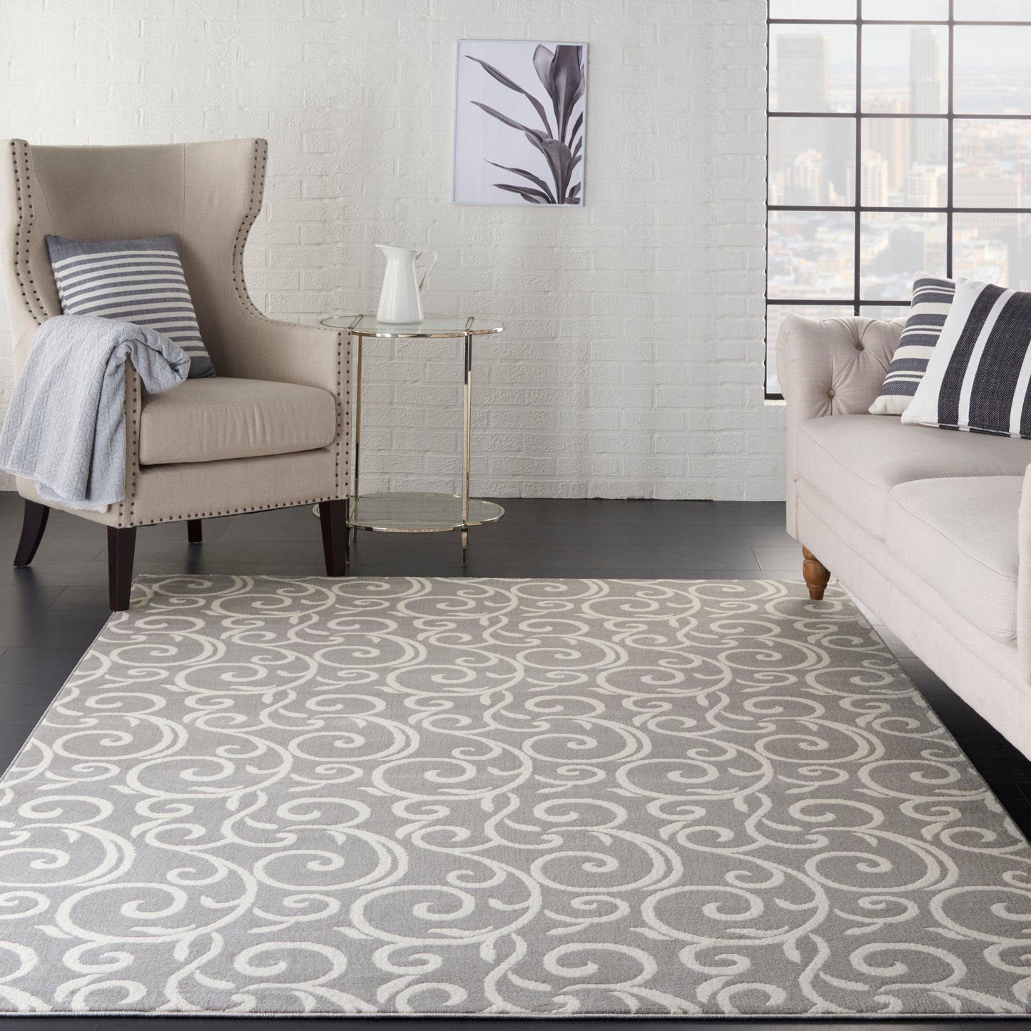 Light gray rug with white swirl pattern in a modern living room; beige tufted armchair, glass-top side table, cushions.