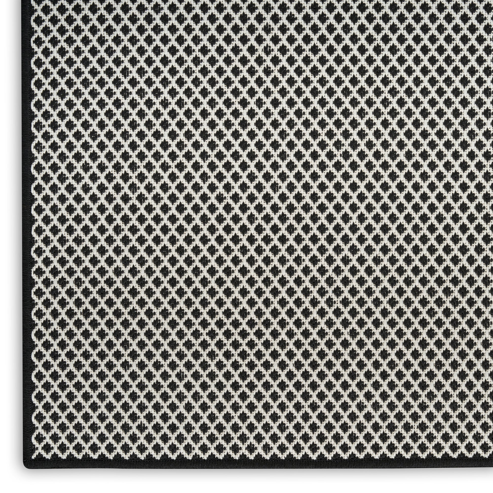 Close-up of a black rug with a silver diamond pattern and black border.