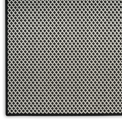 Close-up of a black rug with a silver diamond pattern and black border.