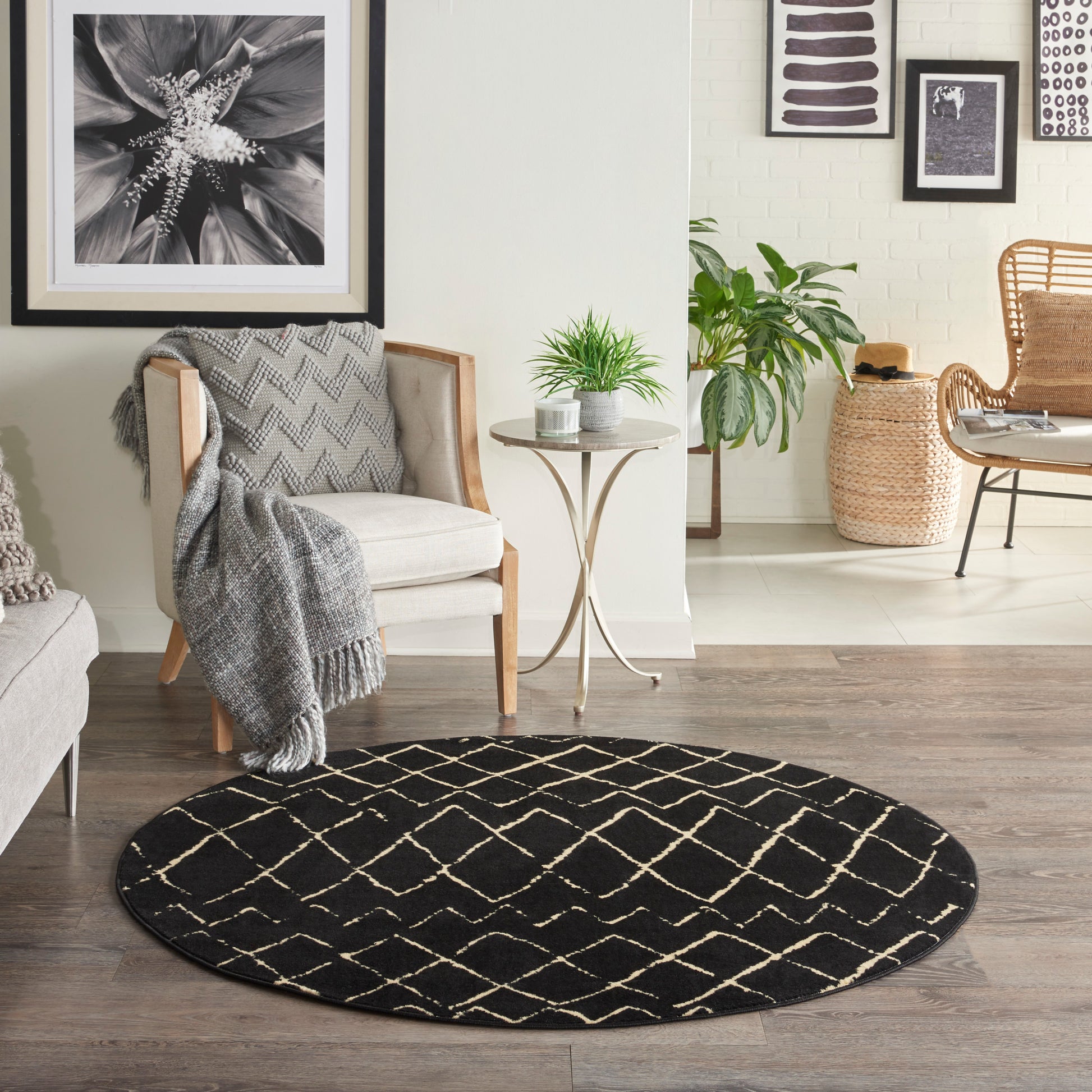 Round black rug with beige lattice in a neutral living room; cream armchair, gray throw, metal side table, and greenery.