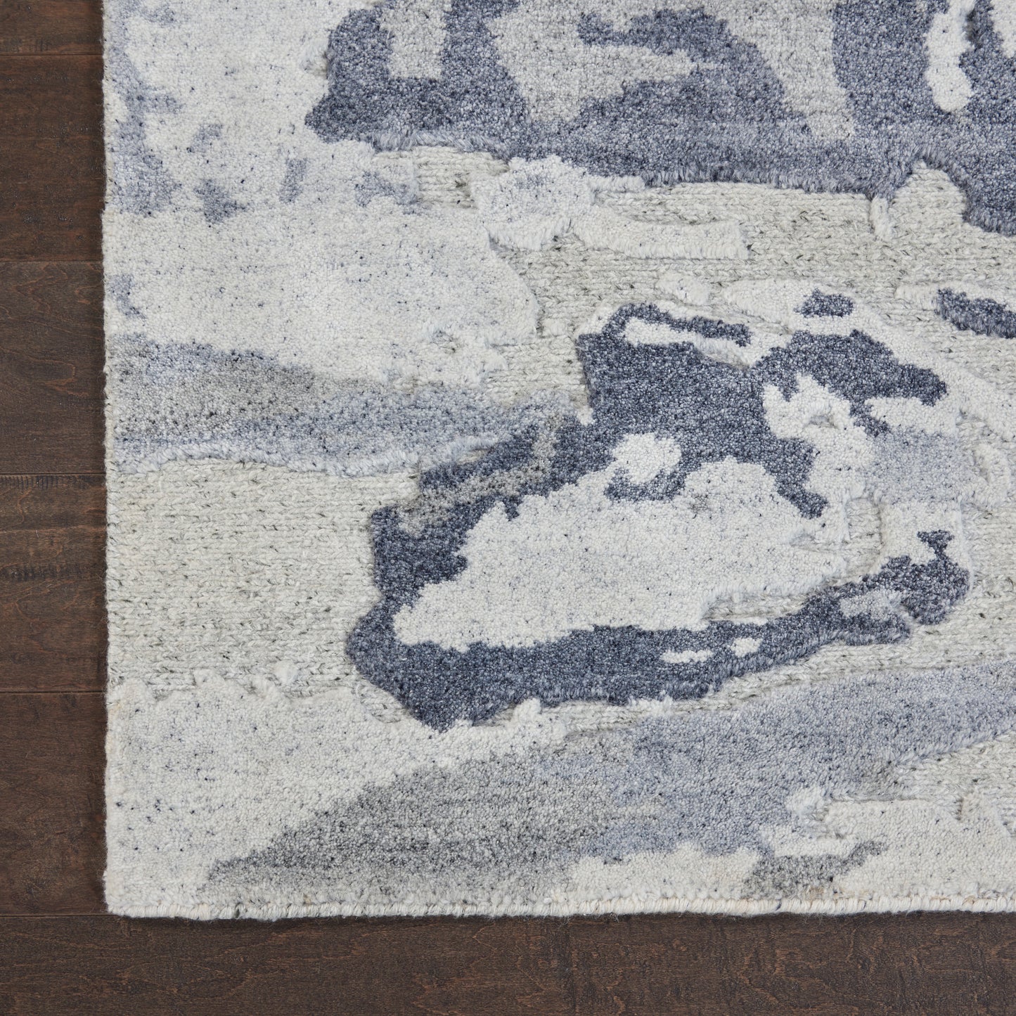 Cream and blue abstract patterned area rug with soft, textured pile on wood floor.