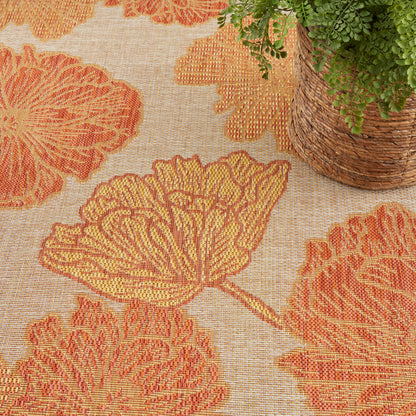 Woven area rug with bold orange botanical leaf pattern on beige background; natural fiber texture, boho coastal style.