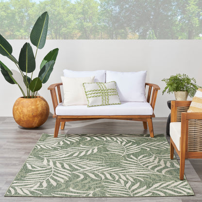 Outdoor rug with a green palm-leaf pattern on a tropical patio; 4' x 6' rug, with a terracotta pot and a tall leafy plant nearby.