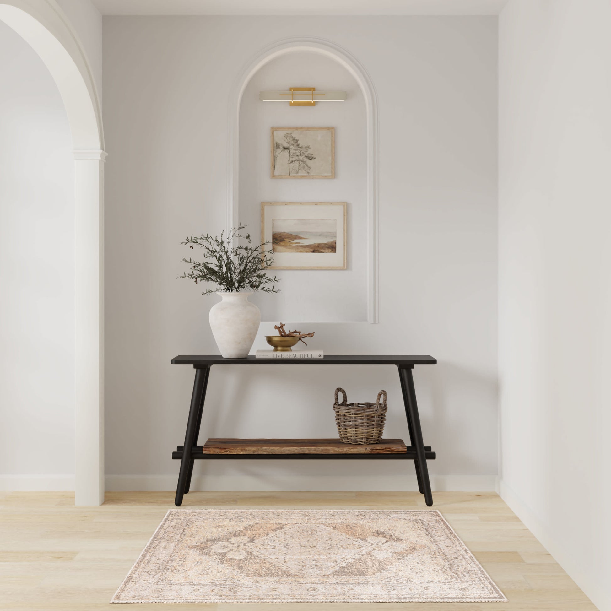 Black mid-century console in an arched alcove with pale walls; vase with greenery, wicker basket, framed prints, beige rug.