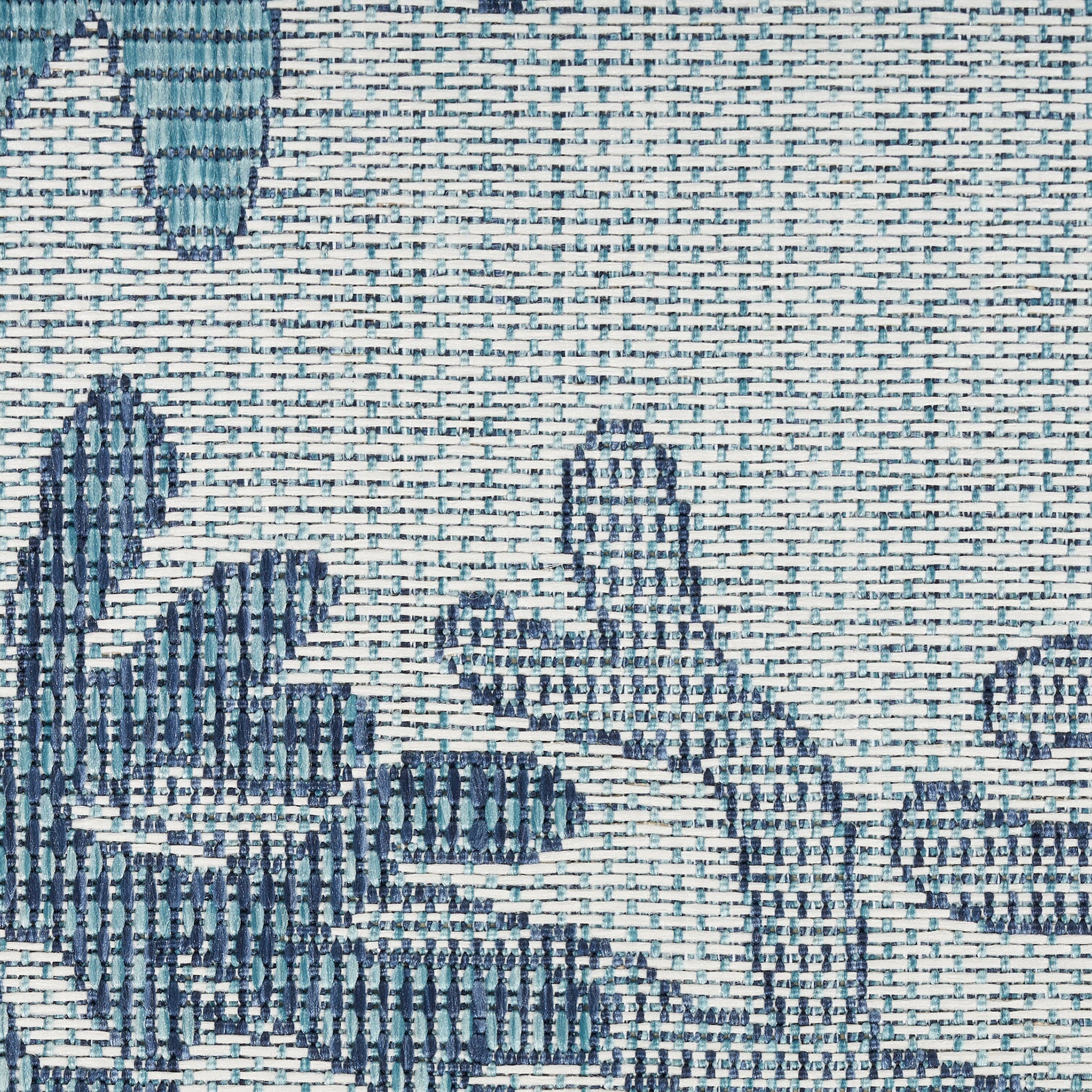 Close-up of textured blue floral jacquard rug with teal and navy leaves on cream background