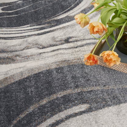 Abstract charcoal, gray and ivory rug with swirled pattern; plush texture beside orange tulips for decor.