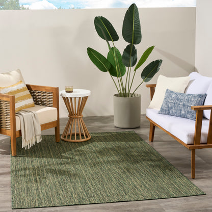 Outdoor patio seating with wooden frames, white cushions, beige throw, white table, large potted tropical plant, green rug.