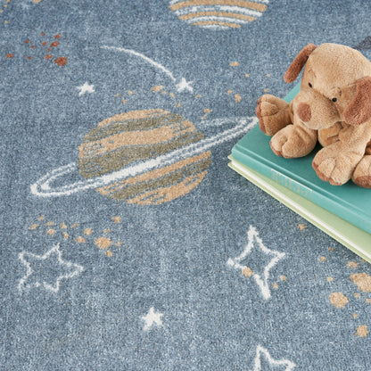 Brown plush dog atop green and teal books on a blue space-themed rug featuring a Saturn-like planet and stars.
