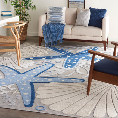 Coastal-area rug with blue starfish motifs on ivory background in a bright living room.