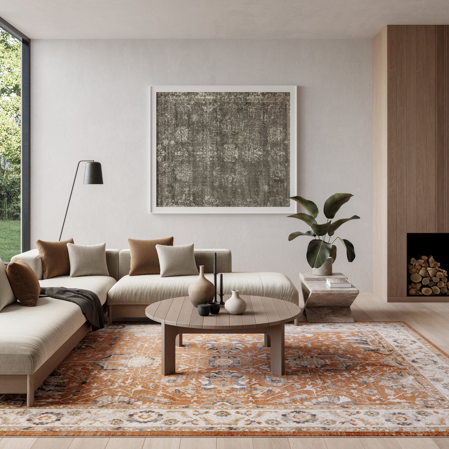 Modern beige sectional living room with a round wood coffee table, abstract art, orange patterned rug, plant, and floor lamp.