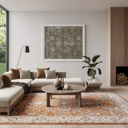 Modern beige sectional living room with a round wood coffee table, abstract art, orange patterned rug, plant, and floor lamp.