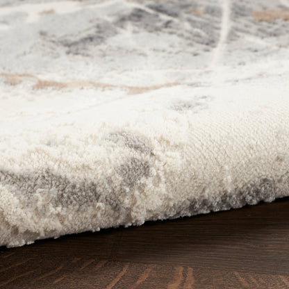 Close-up of a cream-gray plush area rug with a subtle pattern on dark wood floor.