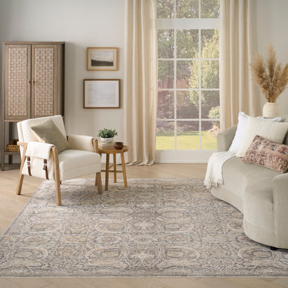 Neutral living room with beige sofa, wooden-frame armchair, side table, woven cabinet, wall art, window, and blue-gray rug.